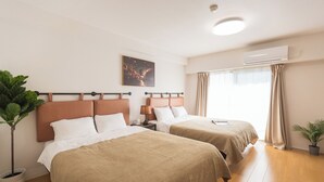A hotel room with two beds, a nightstand, a lamp, an air conditioner, and a window with curtains. - b&Tengachaya (Osaka)