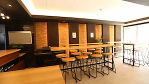 A modern bar area with wooden stools and tables, a whiteboard, and a brick accent wall. - b&Tengachaya (Osaka)