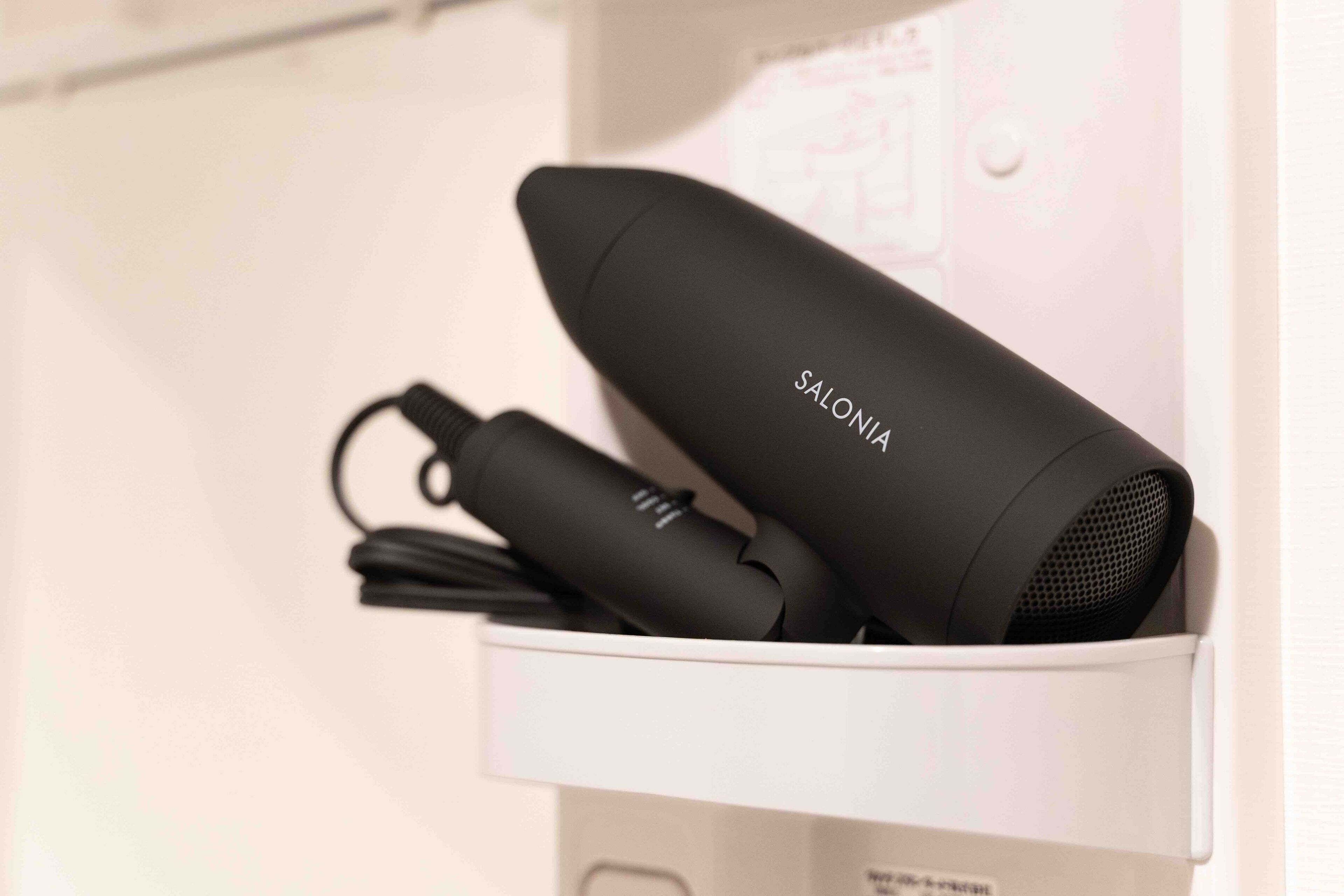 A hairdryer and its accessories in a white drawer.