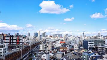 Un paisaje urbano con edificios residenciales densos, una vía ferroviaria destacada y un cielo azul despejado.