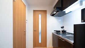 A compact kitchen with a wooden door, a stainless steel sink, and modern appliances. - b&Tengachaya (Osaka)
