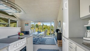 Une cuisine moderne dotée d’un four encastré, d’une cuisinière et d’un coin repas avec une table et des chaises.
