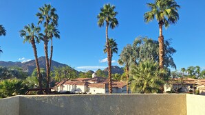 Ein Balkon mit Blick auf Palmen und ein Gebirge.
