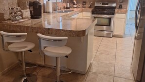 A kitchen with a central island, stainless steel appliances, and a bar area with stools. - Private Home in Greater Palm Springs, La Quinta 
Salt Water Pool and Hot Tub (La Quinta)