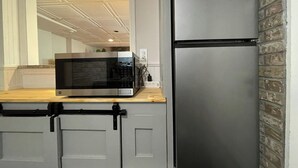 Una cocina con un refrigerador de acero inoxidable, un microondas y una encimera de madera.
