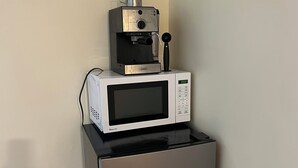Et kompakt køkkenområde med en mikrobølgeovn og en kaffemaskine oven på et Hisense køleskab.