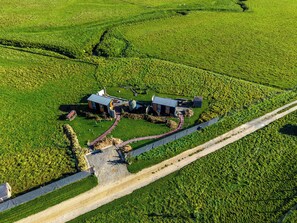 Vista aerea di un'azienda agricola con due edifici, un sentiero sterrato e un'area recintata.