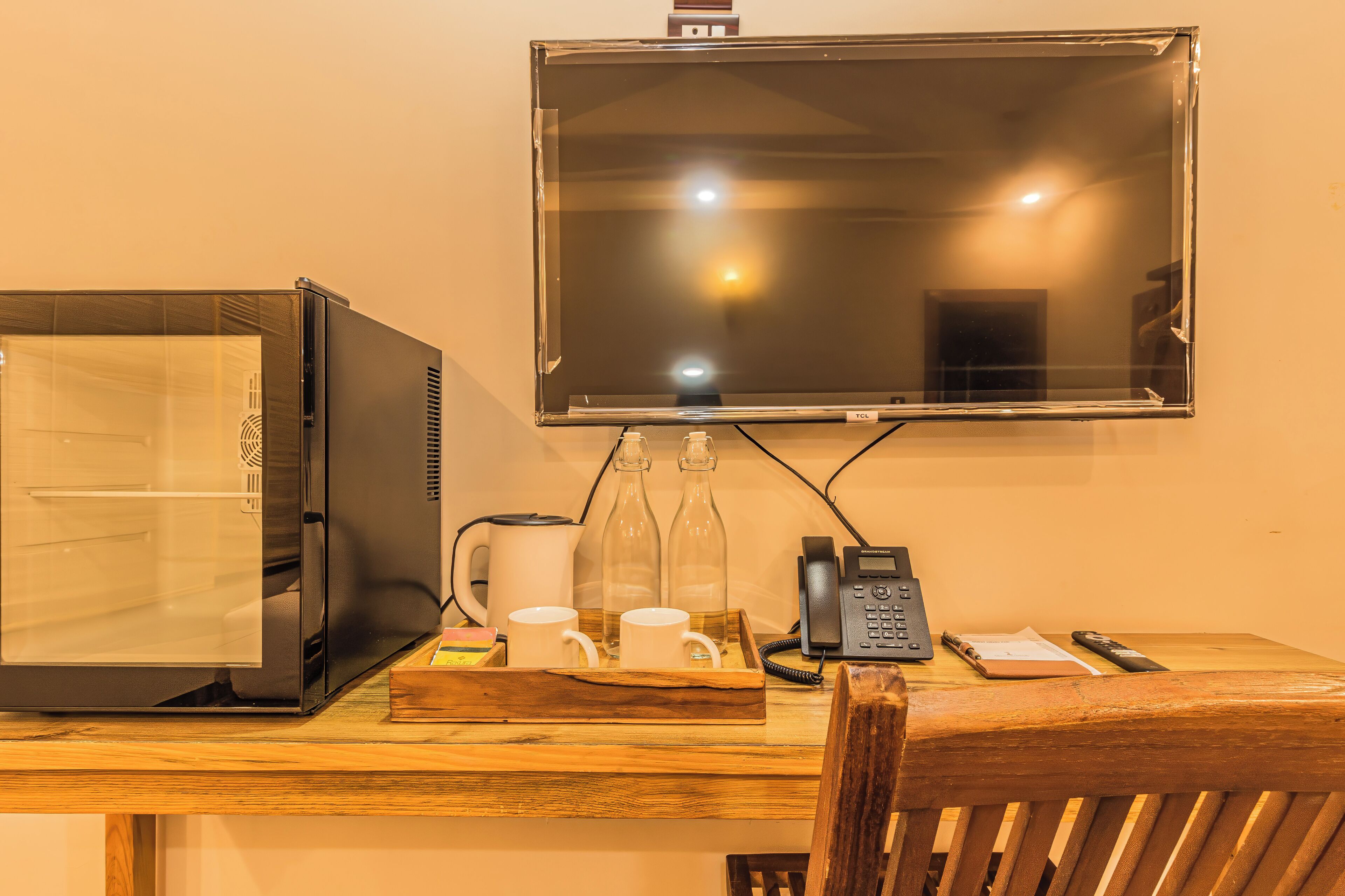 A room with a wooden desk, a black telephone, a glass bottle, and a white mug.