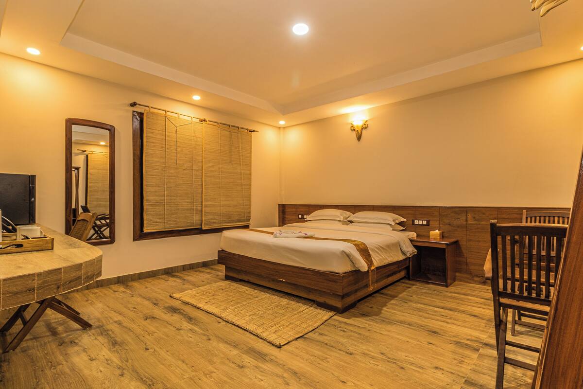 A bedroom with a wooden bed, bedside tables, a desk, and a chair.