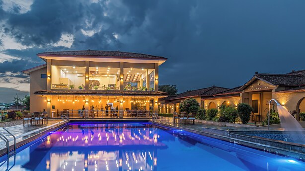 A two-story building with a swimming pool in front. - Munal and Mayur Resort (Kalika)