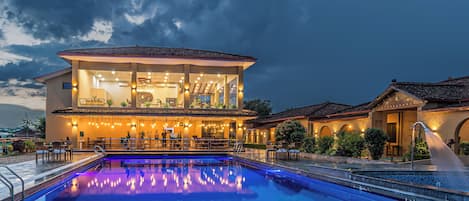 Una piscina al aire libre, sombrillas, sillones reclinables de piscina