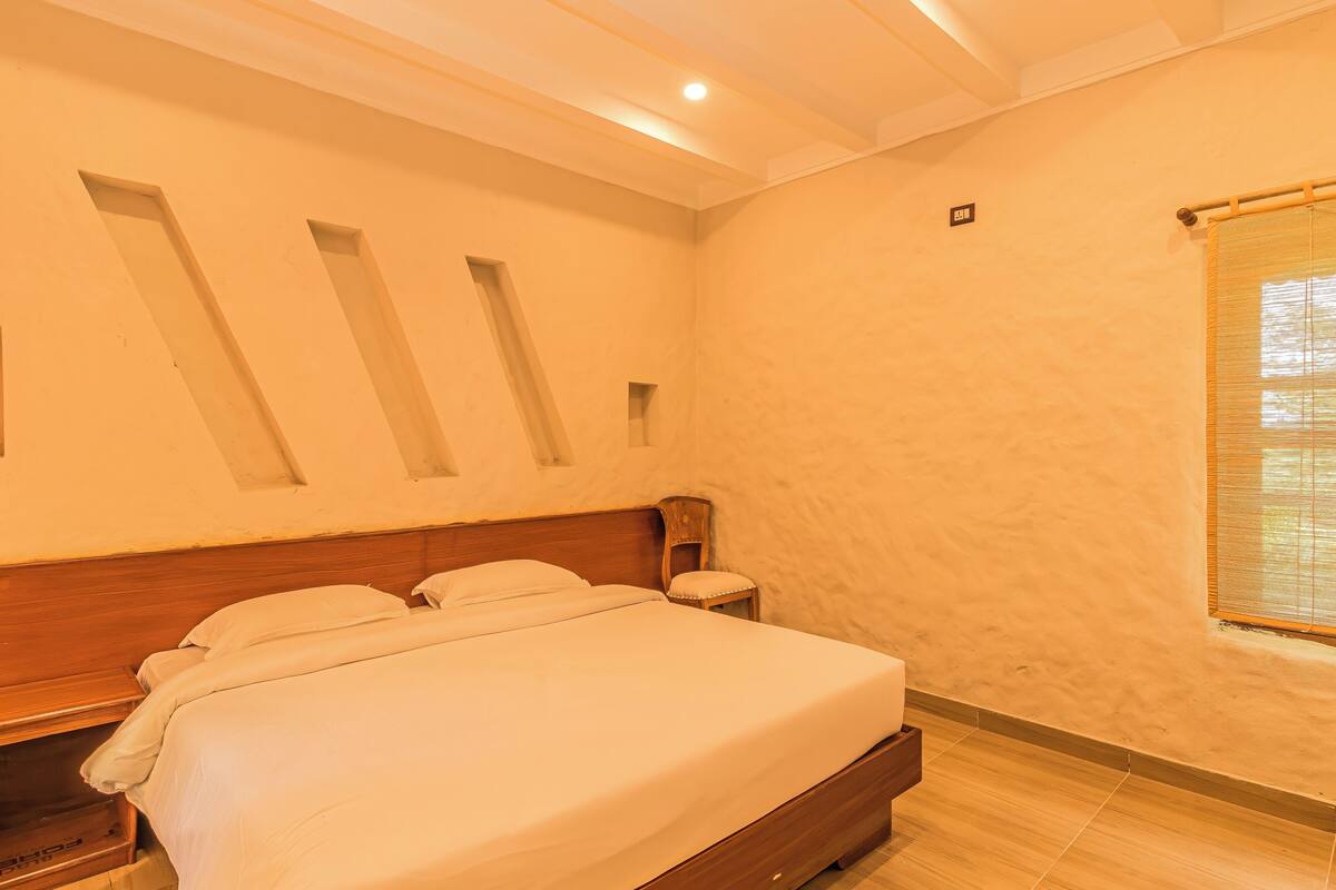 A bedroom with a wooden bed, a nightstand, and a window with blinds.