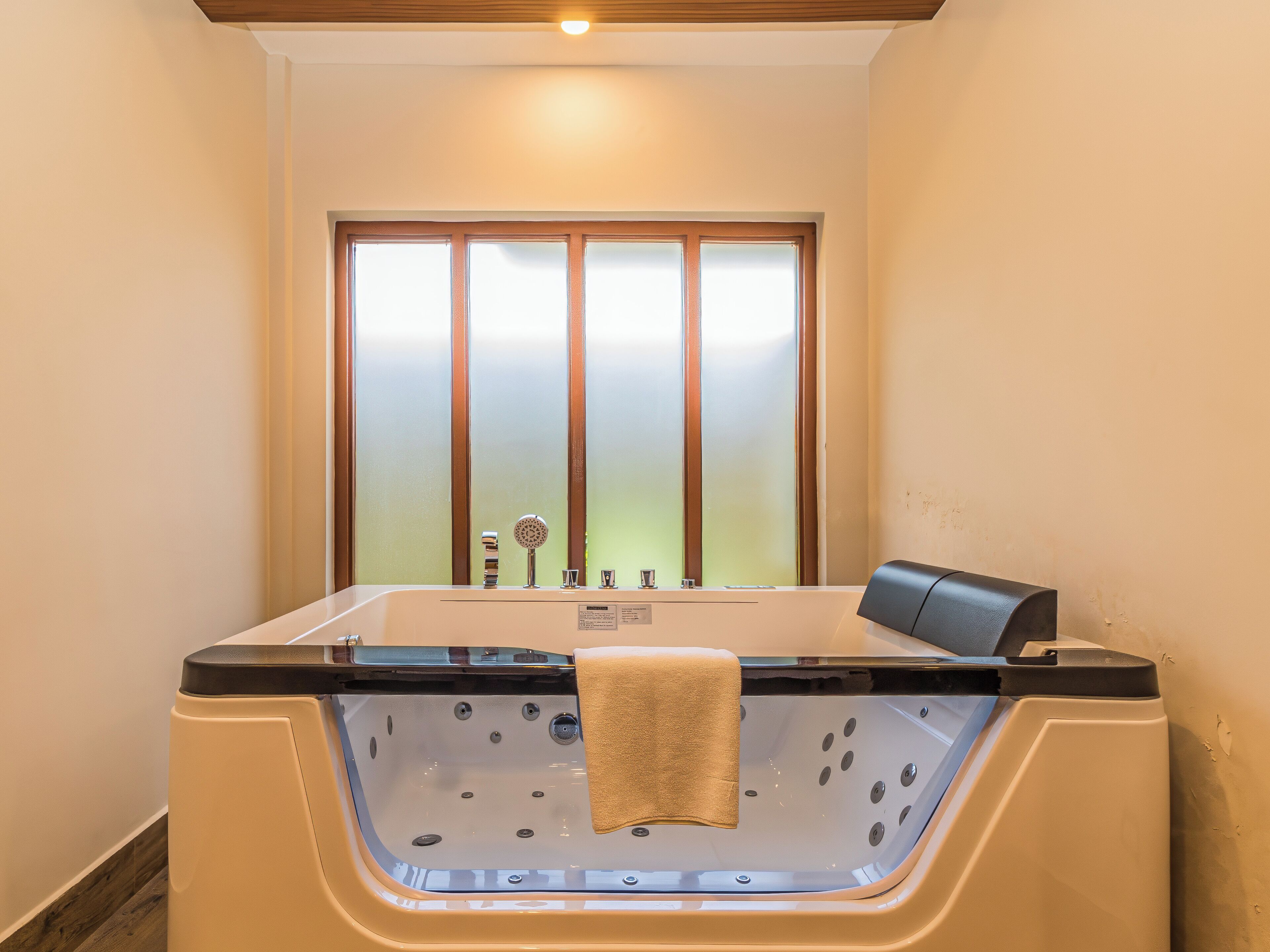 Un cuarto de spa con una bañera grande, ventanas con vidrio esmerilado y una toalla colgando del borde.