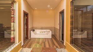 A modern bathroom with a large freestanding bathtub, wooden flooring, and patterned wall tiles. - Munal and Mayur Resort (Kalika)