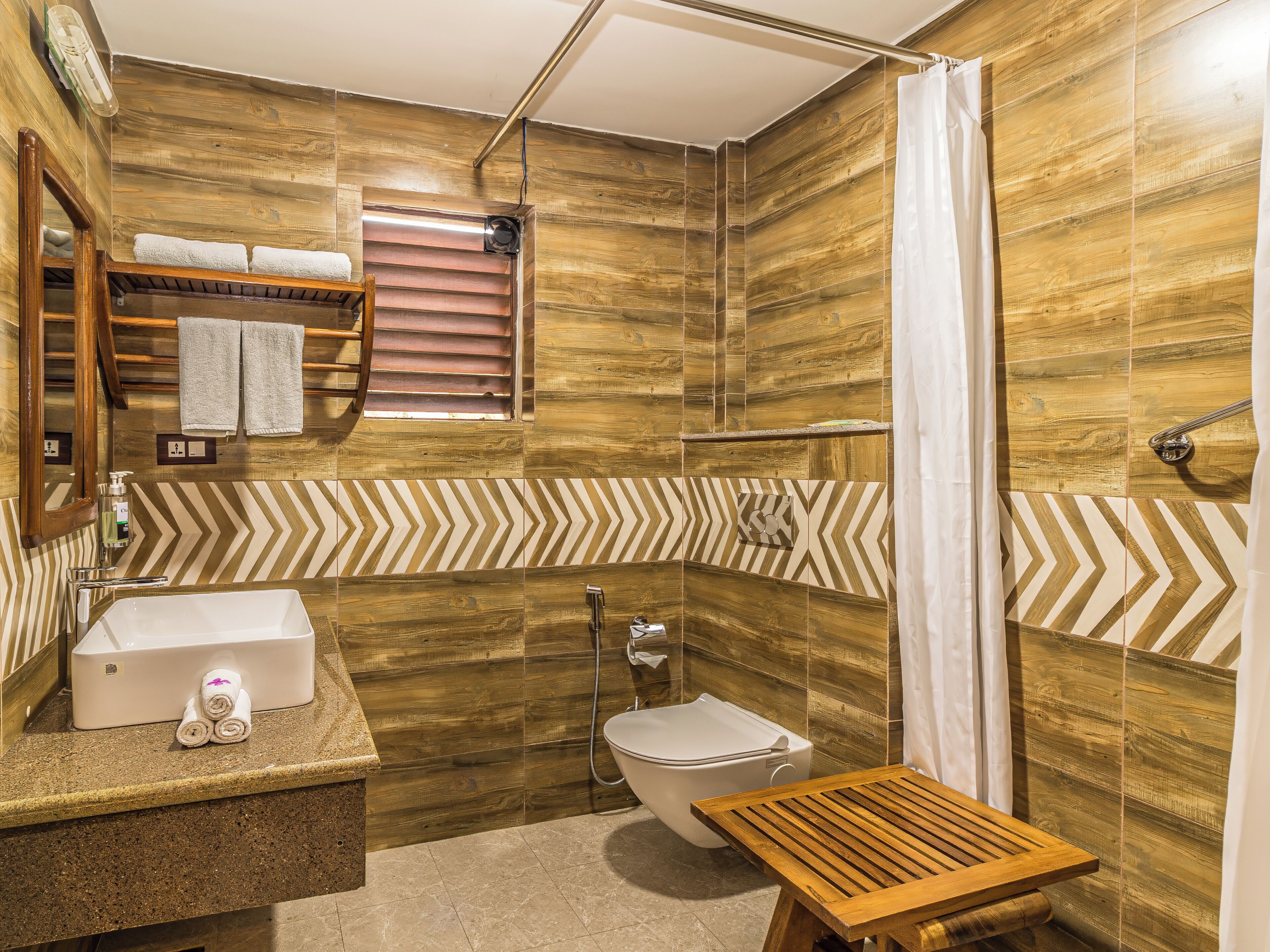 A bathroom with a wooden vanity, a toilet, and a shower area.