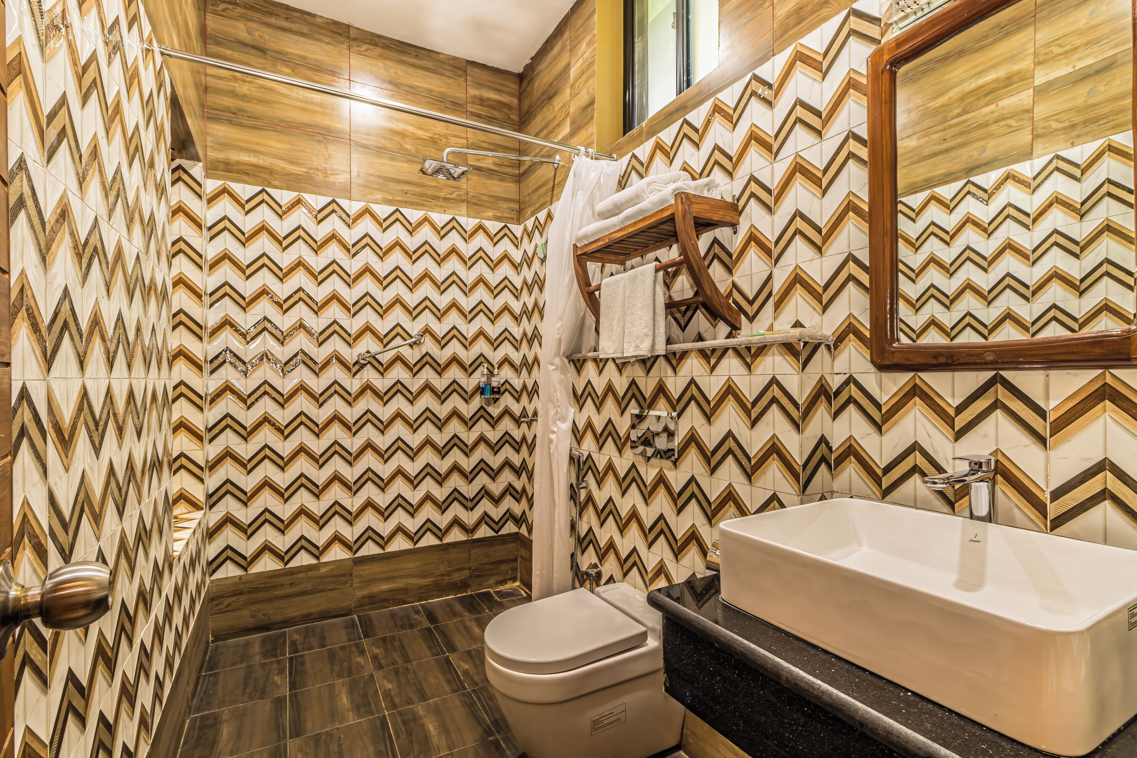 A bathroom with a zigzag patterned wall, a toilet, a sink, and a shower area.