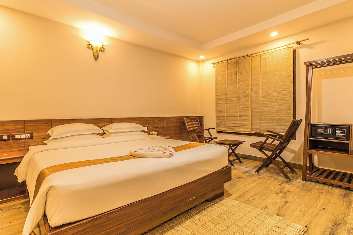 A hotel room with a large bed, a desk, and a chair.