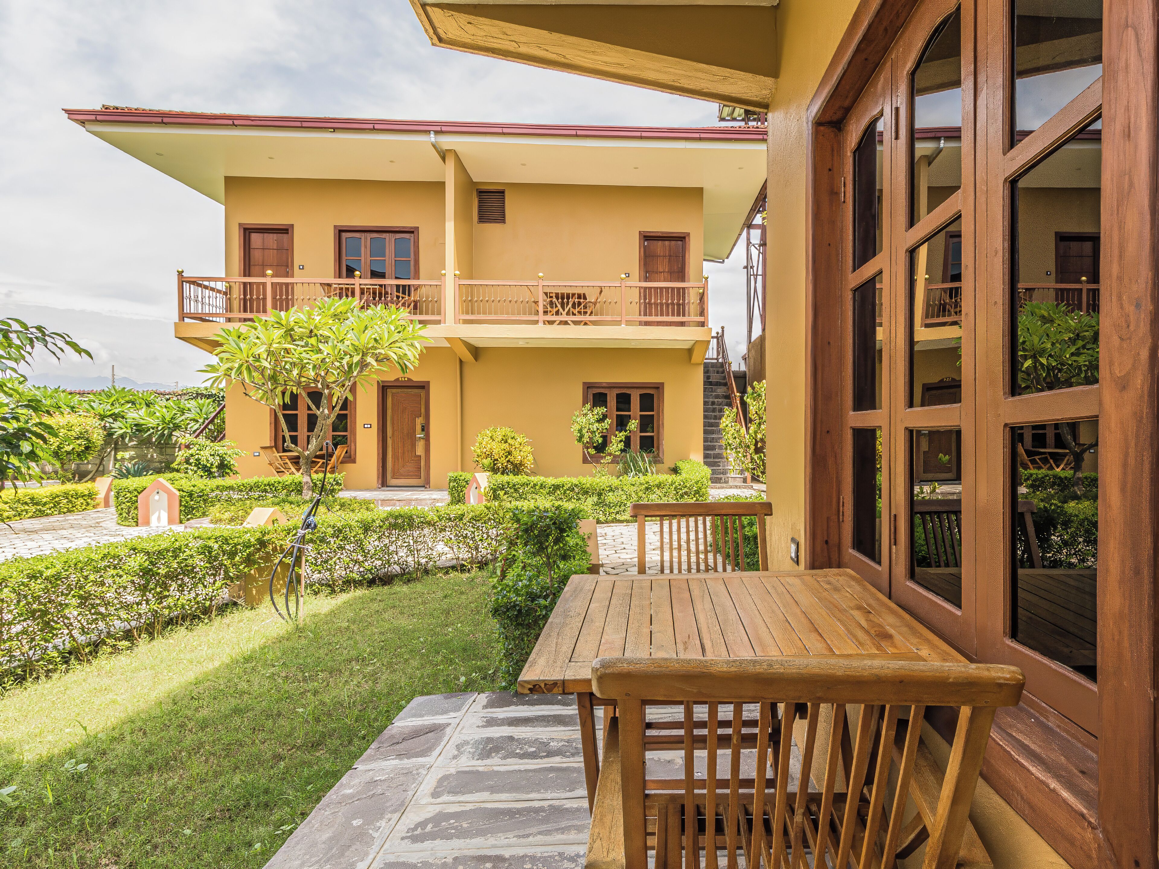Un bâtiment à deux étages doté d’un balcon, d’une table en bois et d’un chemin en pierre.