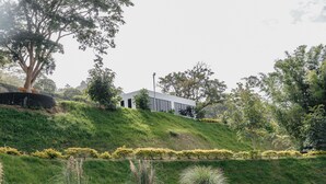 A modern building with a flat roof, surrounded by lush greenery and a well-maintained lawn.