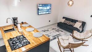 A modern kitchen with a built-in stove, a sink, and a flat-screen TV mounted on the wall.