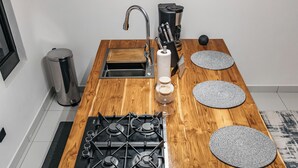 A kitchen with a wooden island, stainless steel sink, and a coffee machine.