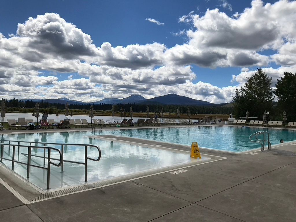 Une piscine avec vue sur les montagnes et un ciel nuageux.