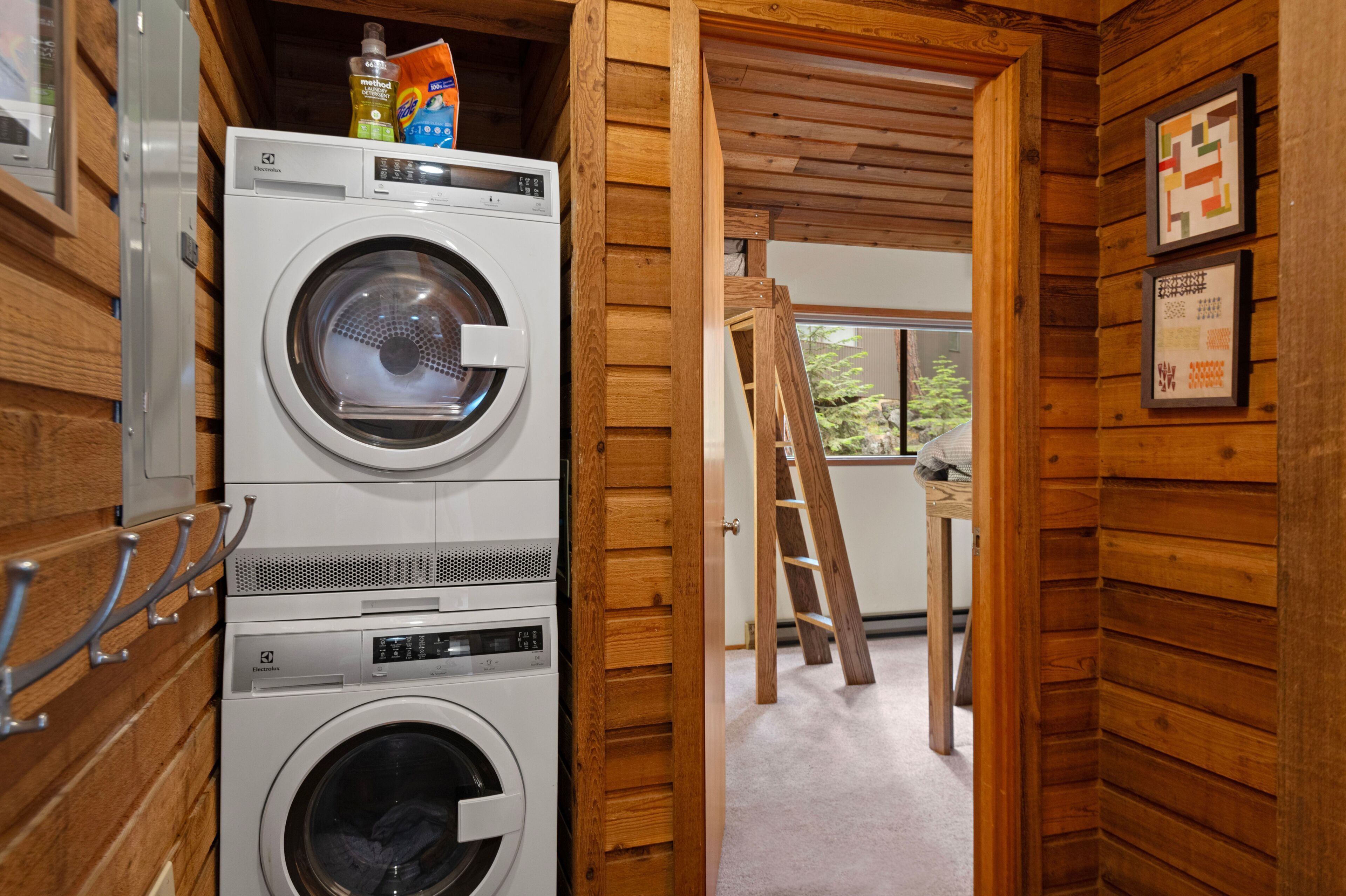 Stacked washer and dryer unit situated in a wood-paneled hallway beside a bedroom.