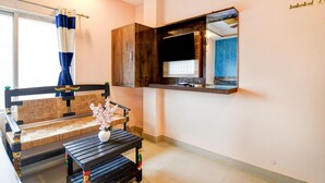 A room with a sofa, a small table with a vase, a mirror, and a window with curtains. - Hotel O Bolpur Central Railway Junction (Bolpur)