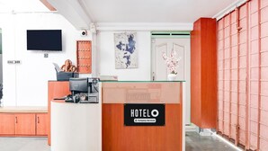 A hotel reception desk with a 'HOTELO' sign, a flat-screen TV, a wooden counter, and a wall-mounted artwork. - Hotel O Bolpur Central Railway Junction (Bolpur)