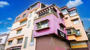 A multi-story building with balconies, a sign indicating a hotel, and a clear blue sky. - Hotel O Bolpur Central Railway Junction (Bolpur)