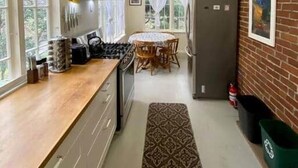 A kitchen with a wooden countertop, a gas stove, a refrigerator, and a dining area with a table and chairs. - Heart of Eastsound-For couples! (Eastsound)