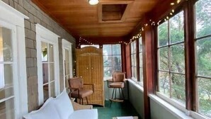 A cozy room with a wooden ceiling, a white sofa, two chairs, a small table, and large windows with a view of greenery. - Heart of Eastsound-For couples! (Eastsound)