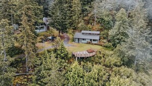 A remote cabin surrounded by dense forest, with a small deck and a clear path leading to the main building. - INSANE VIEWS! HOT TUB! (San Juan County)