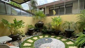 A covered outdoor area with a circular stone and gravel garden, potted plants, and a seating area with chairs. - Thereseplace, cozy 3-bedroom house in the heart of Davao City (Davao City)
