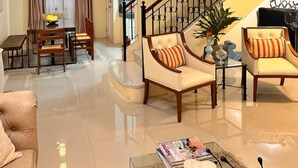 A spacious living room with a high ceiling, a staircase with a wrought iron railing, and a dining area with a table and chairs. - Thereseplace, cozy 3-bedroom house in the heart of Davao City (Davao City)