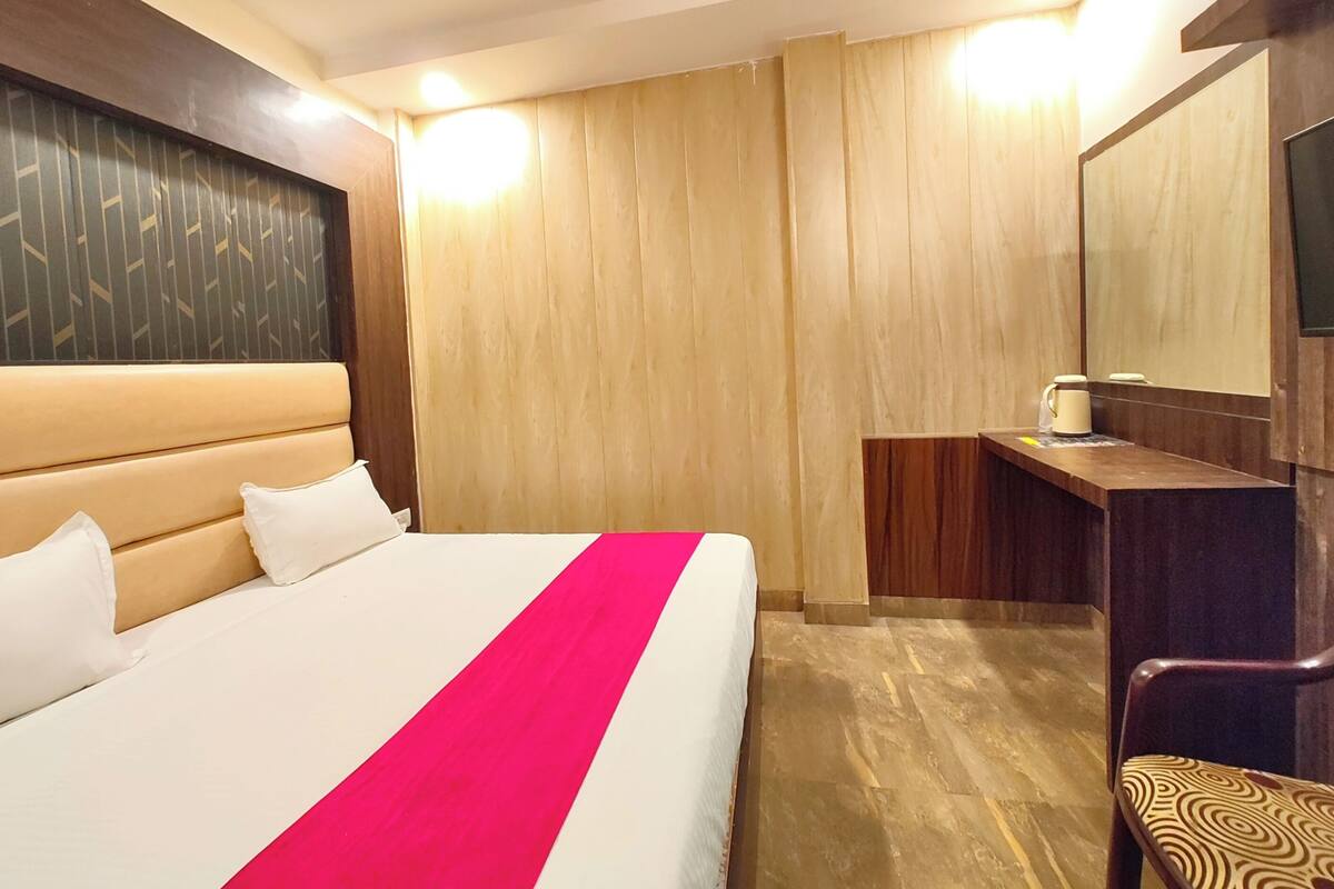 Een hotelkamer met een bed, een houten hoofdbord, een kaptafel met spiegel en een stoel.