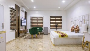 Habitació d'hotel moderna amb un llit gran, una taula de treball, una cadira i una televisió.