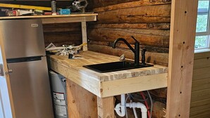 Une cuisine rustique avec des murs en bois, un évier encastré et un réfrigérateur.