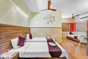 Ein Hotelzimmer mit zwei Betten, Holz-Kopfteilen, einem Deckenventilator, einer Wandleuchte und einem dekorativen Wandbild.