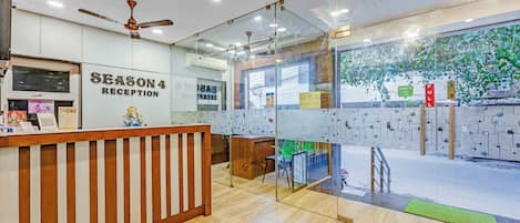 A reception area with a wooden counter, a ceiling fan, and glass walls.