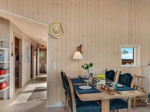 A dining area with a wooden table, chairs, and a view of the kitchen in the background. - 4 Star Holiday Home in Store Fuglede (Store Fuglede)
