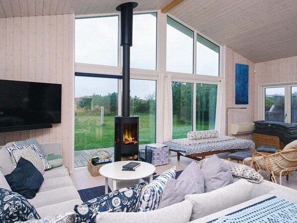 A cozy living room with a fireplace, comfortable seating, and large windows.