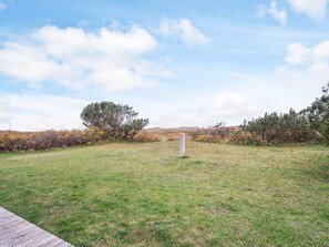 A grassy field with a wooden deck in the foreground and a tall white post in the center. - 4 Star Holiday Home in Store Fuglede (Store Fuglede)