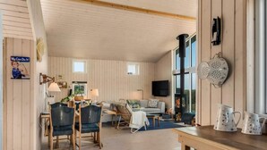 A cozy living room with a fireplace, wooden floors, and a dining area with chairs and a table.