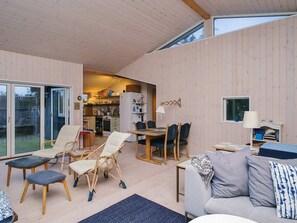 A spacious living area with a dining table, chairs, and a sofa. There is a kitchen visible in the background. - 4 Star Holiday Home in Store Fuglede (Store Fuglede)