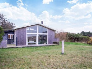 A modern wooden house with large glass windows and a deck.