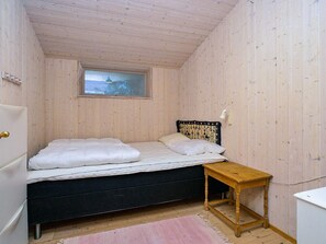 A bedroom with a bed, a small table, and a window.