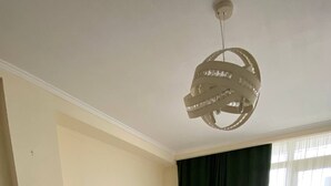 A bedroom with a bed, a small white cabinet, and a wooden floor. - Charming apartment in marvelous Tbilisi with AC (Tbilisi)