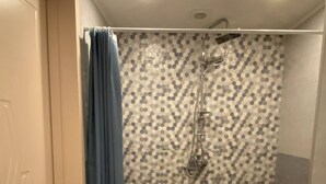 A bathroom with a checkered floor, a shower with a hexagonal tile pattern, and a blue curtain. - Charming apartment in marvelous Tbilisi with AC (Tbilisi)