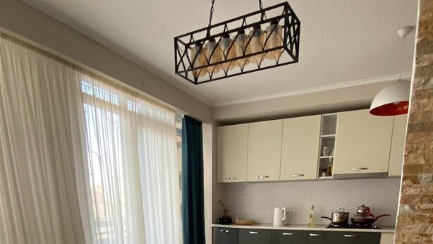 A modern kitchen with wooden flooring, a dining table, and a kitchen island. - Charming apartment in marvelous Tbilisi with AC (Tbilisi)